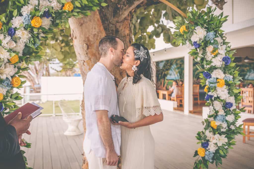 Bride and groom kiss under arch