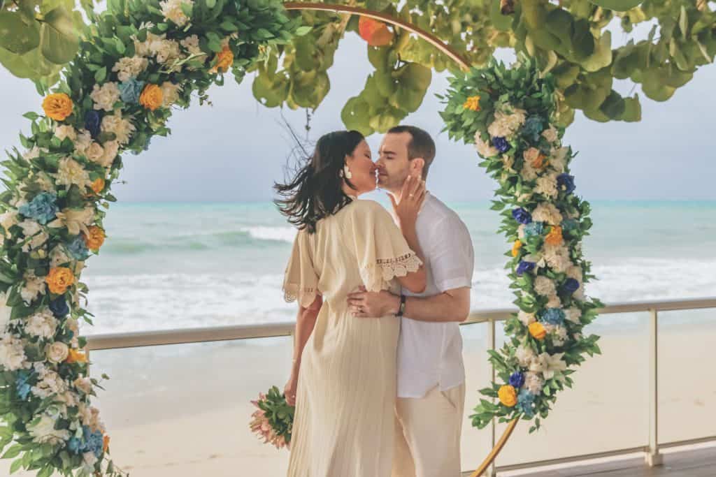 Bride and groom kiss under arch